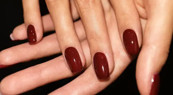 Dłonie z idealnie pomalowanymi na głęboki, wiśniowy kolor paznokciami. To zdecydowanie trendy paznokcie wiosenne, które dodają elegancji.