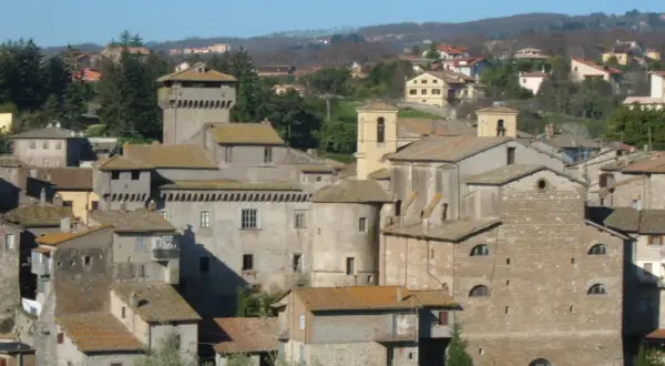 Borgo medievale di Carbognano, Viterbo, con torri e case in pietra sotto un cielo azzurro.