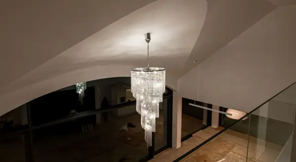 Elegancki zwis do lampy z kryształkami lśni w nowoczesnym wnętrzu z wysokim sufitem.