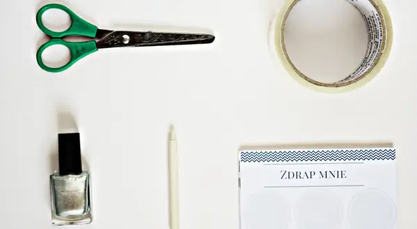 Potrzebne do zrobienia zdrapki na kartce: nożyczki, taśma, srebrny lakier, biała kredka i kartka z napisem "ZDRAP MNIE".