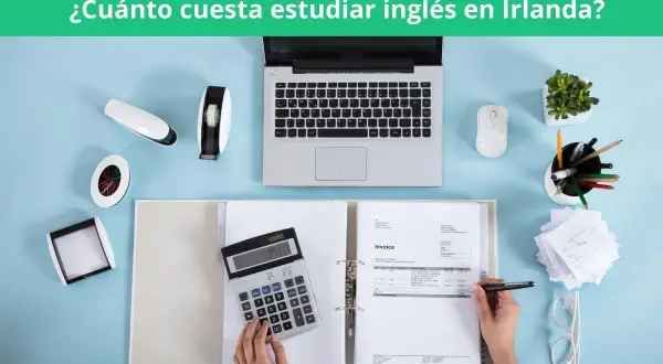 Calculadora, portátil y facturas sobre escritorio azul. Planificando el coste de aprender inglés en Irlanda.