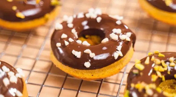 Deliciosos donuts de calabaza cubiertos de chocolate y trocitos crujientes.