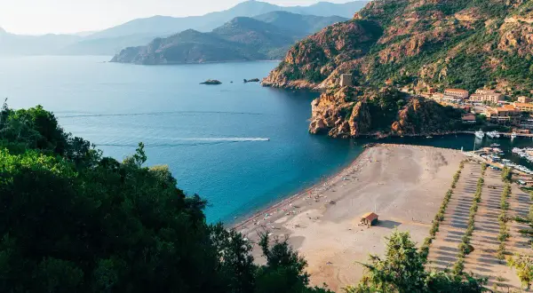 Malownicza zatoka z plażą i miasteczkiem, idealne miejsce na korsyka wczasy all inclusive.