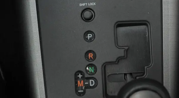 Panel z przyciskami skrzyni biegów: P, R, N, M-D. Obok przycisku "SHIFT LOCK" znajduje się otwór do jego zwolnienia.
