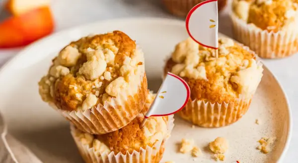 Saftige Apfel Streusel Muffins mit süßer Kruste, dekoriert mit kleinen Apfel-Fähnchen. Ein Genuss für jeden Anlass.