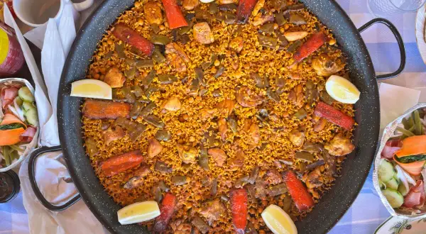 Paella gigante con pollo, judías verdes, pimientos rojos y limón. Los ingredientes paella lucen deliciosos en este plato tradicional español.
