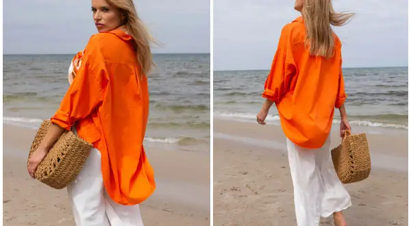 Kobieta w pomarańczowej koszuli i białych spodniach na plaży. Idealne outfity na lato, z plecioną torbą.