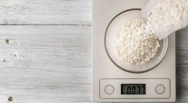 Balanza digital muestra 0.077 kg de arroz en un bol. Ideal para calcular cuánto arroz por persona.