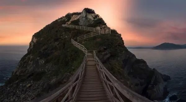 Pasarela de madera serpentea hacia la cima de un acantilado en Galicia, con el mar y un cielo crepuscular de ensueño. Unos de los miradores más espectaculares.