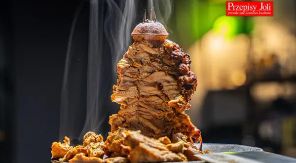 Gorący, parujący kebab z mięsa mielonego, obracający się na rożnie, z chrupiącymi kawałkami mięsa na talerzu.