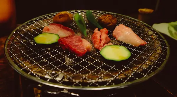 Kött och grönsaker grillas på en rund grill. Ett perfekt yakiniku recept för en mysig kväll.