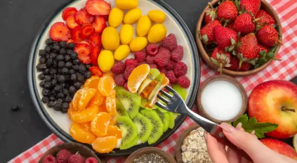Kolorowa uczta dla ciała: truskawki, borówki, maliny, kumkwaty, kiwi i mandarynki. Idealna dieta warzywno owocowa na talerzu.
