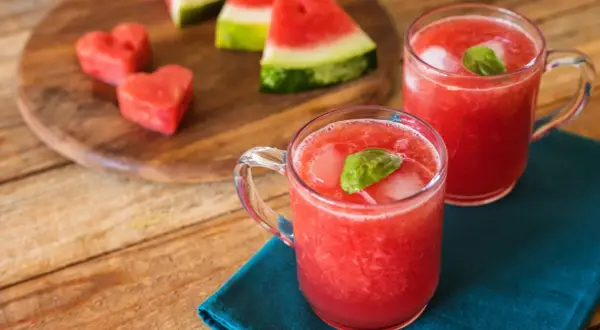 Refrescante bebida de sandía con un toque de limón, servida con hielo y hojas de albahaca.