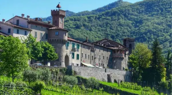 Borgo medievale con torre dell'orologio, circondato da colline verdi. Un vero gioiello, forse il paese più bello della Garfagnana.