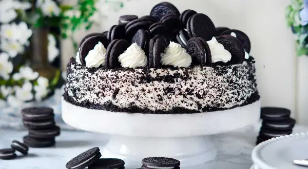 En imponerande oreo tårta, täckt med krossade kakor och dekorerad med hela oreos och fluffig grädde. Perfekt för alla kakälskare!