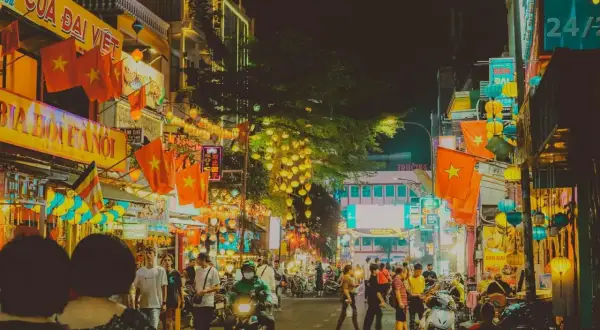 Tętniąca życiem nocą ulica w Ho Chi Minh (miasto), ozdobiona flagami Wietnamu i lampionami.