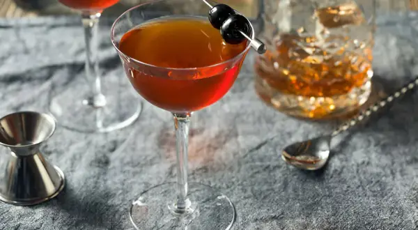 Cocktail au whisky garni de cerises, servi avec un verre de whisky et un jigger. Le whisky est-il bon pour les artères ? Une question à méditer.