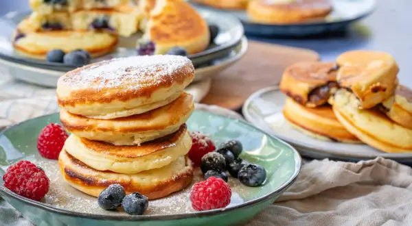Fluffige Buttermilch Pancakes, bestäubt mit Puderzucker und garniert mit frischen Beeren. Ein Genuss für jeden Morgen!