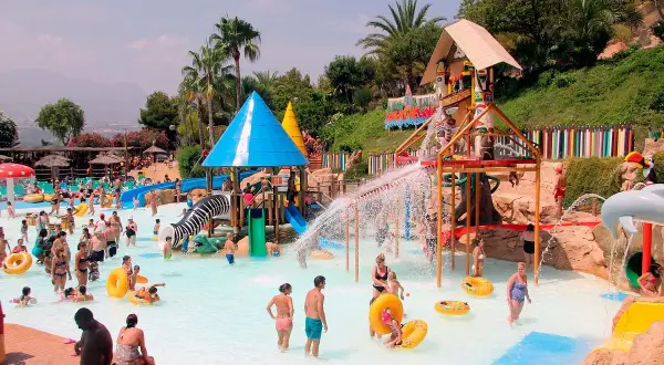 En livlig dag på Aqualandia Benidorm med folk som njuter av vattenrutschkanor och pooler under en solig himmel.