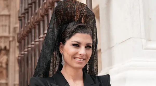 Mujer con peinado boda gitana, velo de encaje negro y pendientes largos. Sonríe con elegancia.