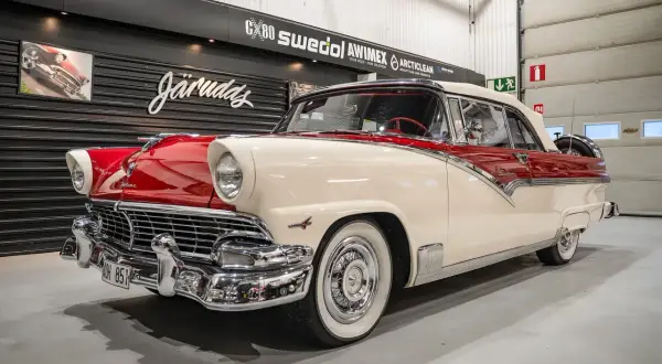 En skinande röd och vit Ford 56 cabriolet står i ett garage.