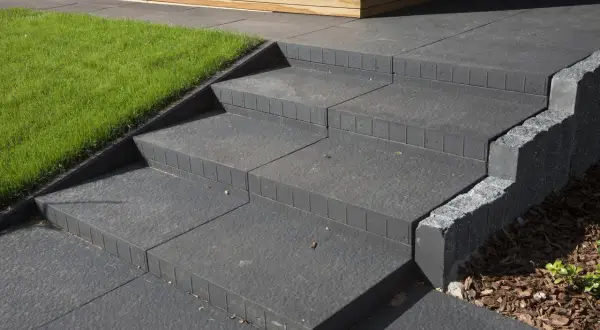 Schody z bloczków betonowych do ogrodu: praktyczny poradnik, jak samemu zrobić schody z bloczków betonowych do ogrodu, z zieloną trawą i drewnianą elewacją.