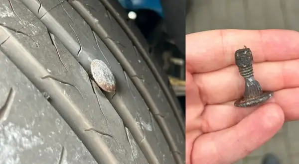 Przebita opona z wbitym gwoździem. W dłoni trzymam wyjęty z opony metalowy element, który spowodował uszkodzenie.