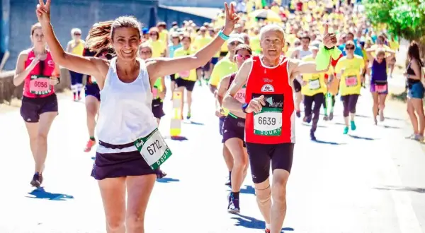 Uśmiechnięci biegacze na maratonie, radość i determinacja. Jak przygotować się do maratonu? Warto czerpać inspirację z ich pozytywnej energii!