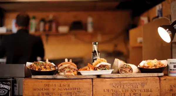 Kebab, burger, frytki i inne dania na drewnianych skrzynkach.