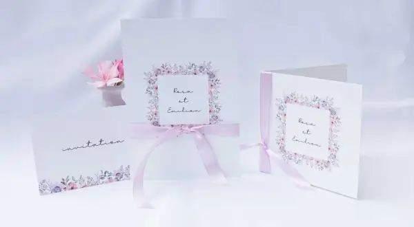Trois faire-part de mariage délicats, ornés de fleurs pastel et de rubans roses. L'un d'eux mentionne "Rosa et Emilien".