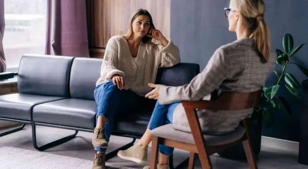 Kobieta na kozetce słucha terapeuty. Rozmowa o psychoterapii i psychologii w przytulnym gabinecie.