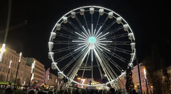 Nocny plac wolności poznań rozświetla ogromne koło widokowe. Tłumy ludzi spacerują wśród świątecznych iluminacji.