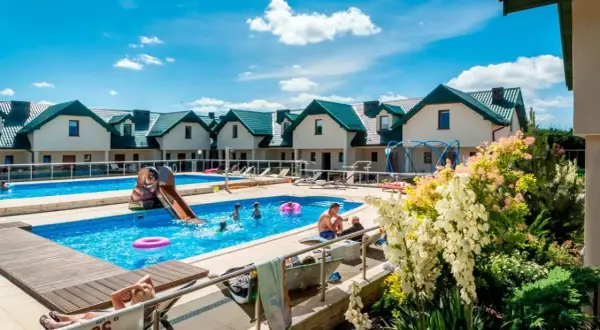 Rodzinny wypoczynek w domkach apartamentowych Fulay Premium. Dzieci bawią się w basenie ze zjeżdżalnią, dorośli relaksują się na leżakach.