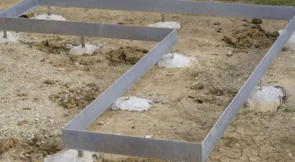 Metallrahmen auf Betonfundamenten für ein neues Haus. Das punkt fundament ist vorbereitet.