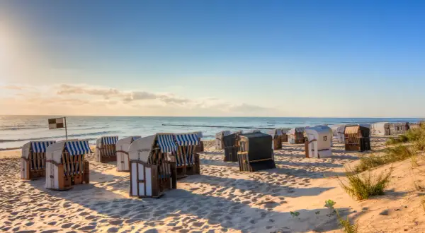 Reihe von Strandkörben am Strand Deutschland, mit Blick auf das Meer und den blauen Himmel.