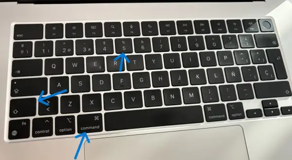 Aprende como hacer una captura de pantalla en el ordenador. Las flechas señalan las teclas Command, Shift y 5.