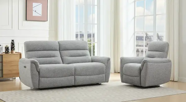 A grey recliner sofa and armchair in a bright living room with large windows.