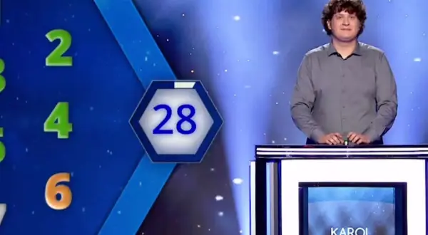 Karol Fedoruk w studiu telewizyjnym, obok planszy z liczbami i wynikiem 2400.