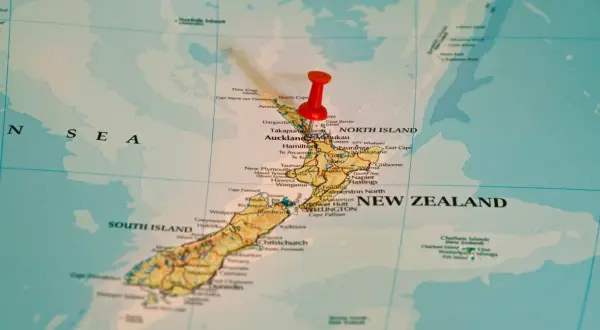 Czerwony pinezka zaznacza Nową Zelandię na mapie. To państwo wyspiarskie, które geograficznie należy do Oceanii, choć kulturowo i politycznie często kojarzone jest z Australią, która leży na kontynencie australijskim.