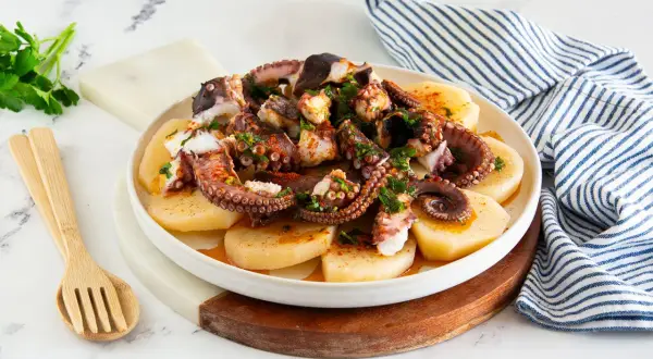 Piatto di polpo alla gallega, con tentacoli succulenti su patate affettate, condito con paprika e prezzemolo fresco.
