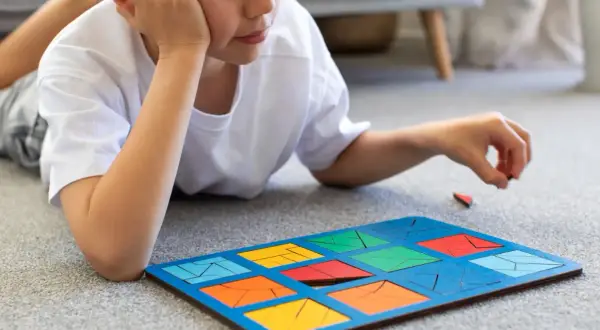 Chłopiec z ADHD układa kolorowe klocki na dywanie. To świetne zabawy dla dzieci z ADHD, rozwijające koncentrację i zdolności manualne.