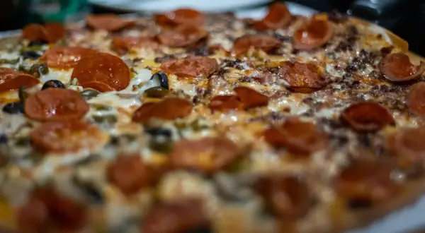 Pyszna pizza z pepperoni i oliwkami, idealna do pieczenia w wysokiej temperaturze.