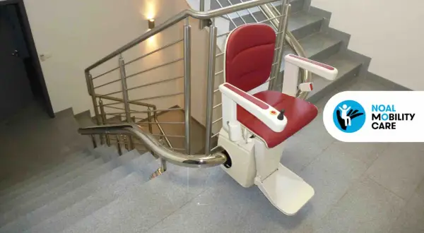 Servoscala condominio rosso e bianco, installato su una scala con corrimano in acciaio. Migliora l'accessibilità.