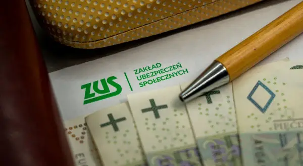 Zwolnienie z ZUS? Na papierze z logo ZUS leżą polskie banknoty i długopis.