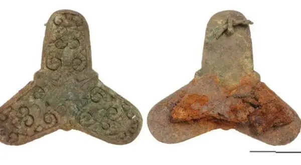 Zwei bronzene Artefakte, ein gut erhaltenes mit Verzierungen, das andere stark verrostet, stammen aus einem Wikinger Grab.