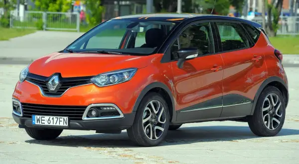 Pomarańczowy Renault Captur 2015 z czarnym dachem i pomarańczowymi akcentami stoi na placu.