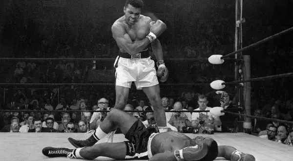 Muhammad Ali stands over a fallen opponent, embodying his famous quote to float like a butterfly and sting like a bee.