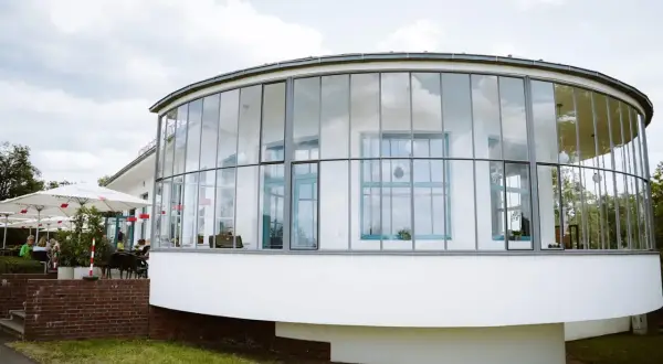 Ein modernes Gebäude mit runden Glasfronten, das an einen Aussichtsturm erinnert. Hier finden sich sicher einige Geheimtipps Dessau.