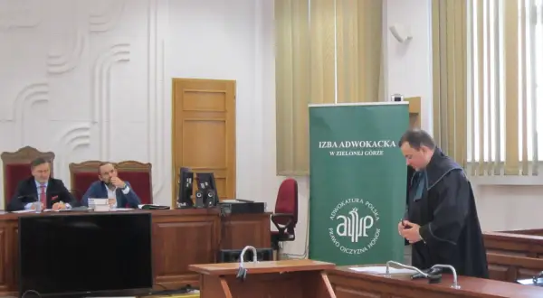 Sąd w Zielonej Górze: dwaj mężczyźni w togach siedzą za stołem, jeden w todze stoi obok.