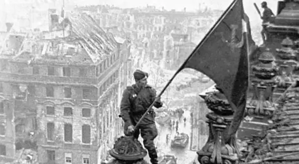 Soldat hisst Flagge über zerstörter Stadt. Berlin, 8. Mai Feiertag.